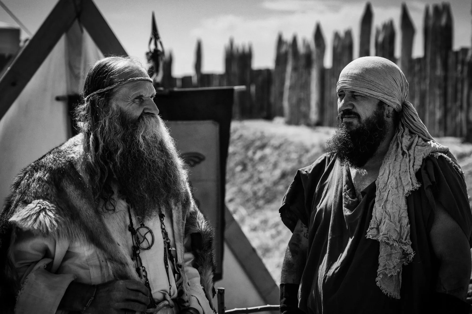 Black-and-white photograph of two bearded historical performers in conversation