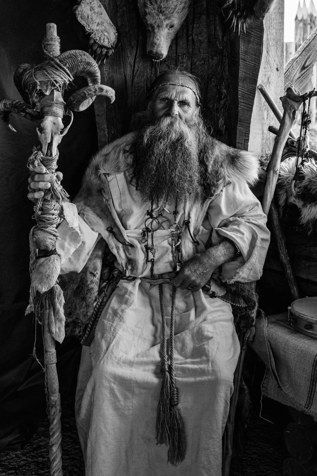 Black-and-white portrait of a seated bearded man holding a carved staff