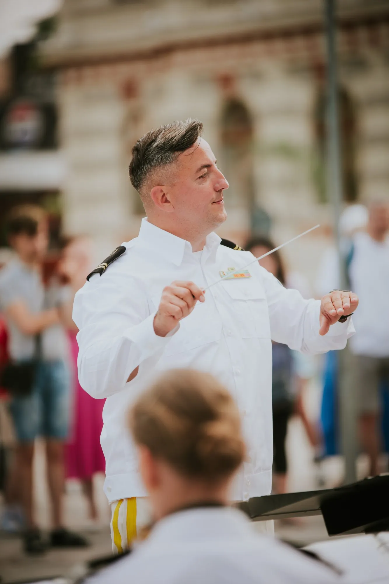 Military band conductor gesturing during an outdoor performance