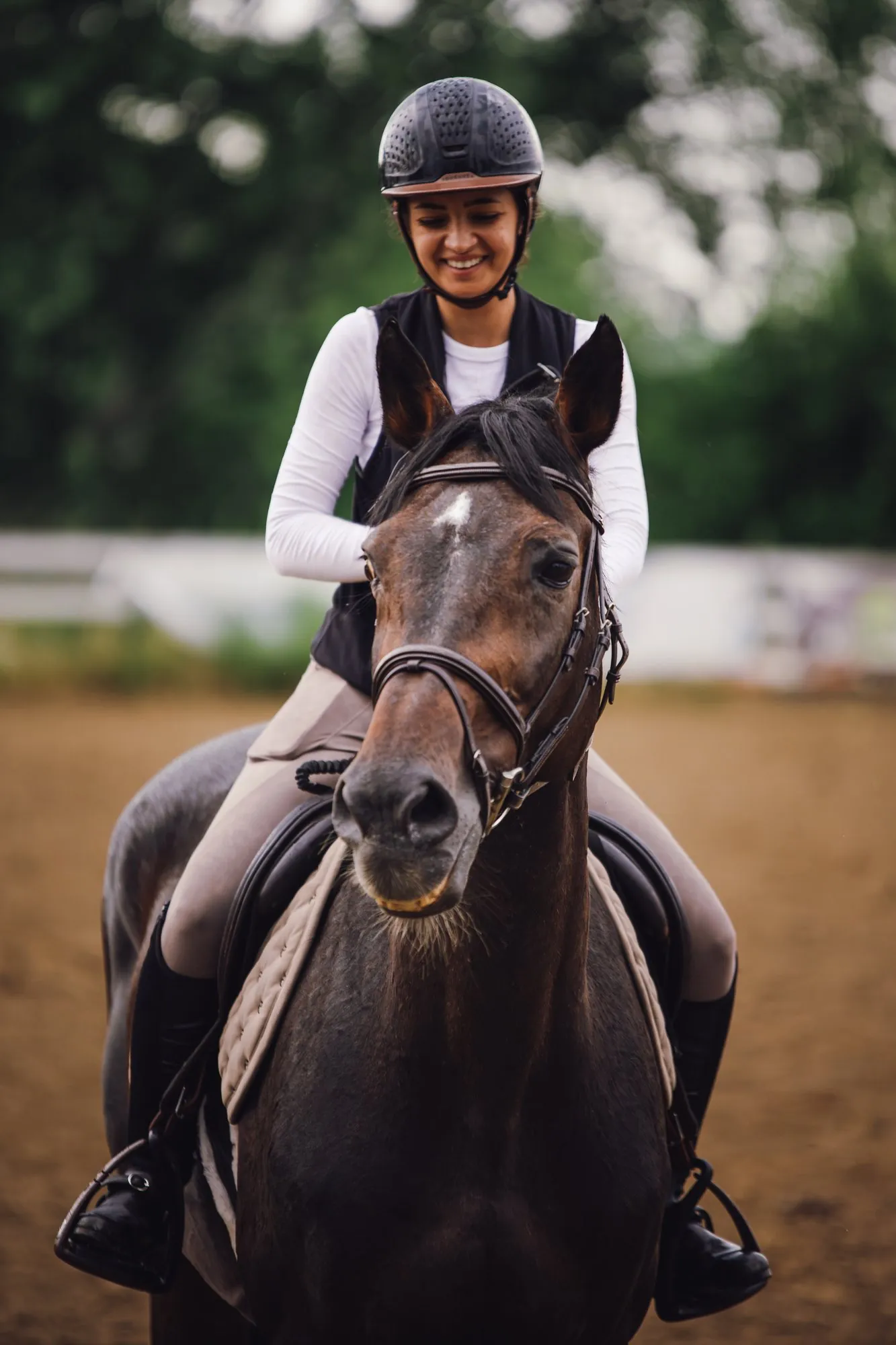 Close frontal portrait of a smiling rider and a dark horse