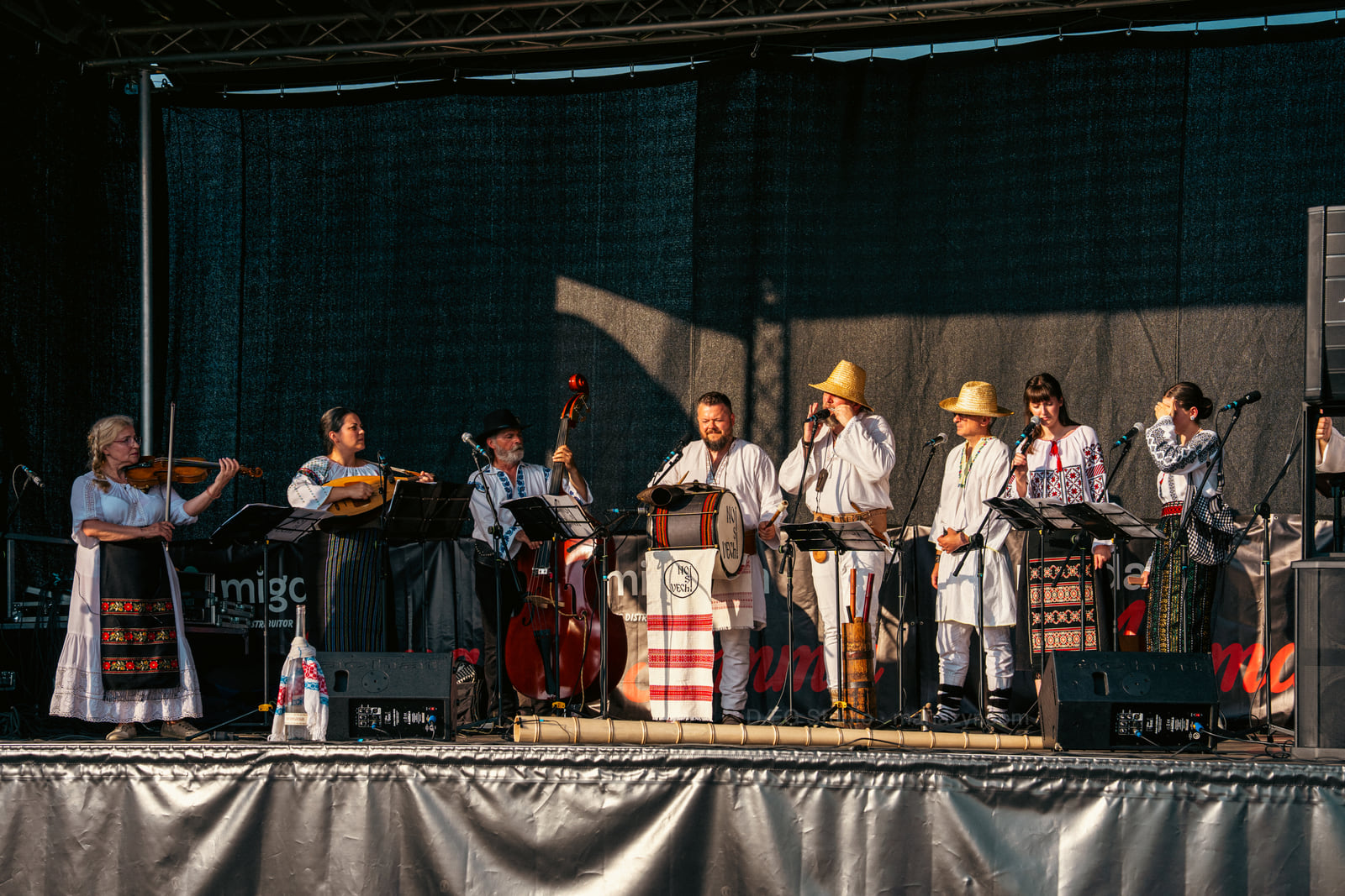 Wide view of the complete folk ensemble gathered with strings, percussion and traditional wind instruments.