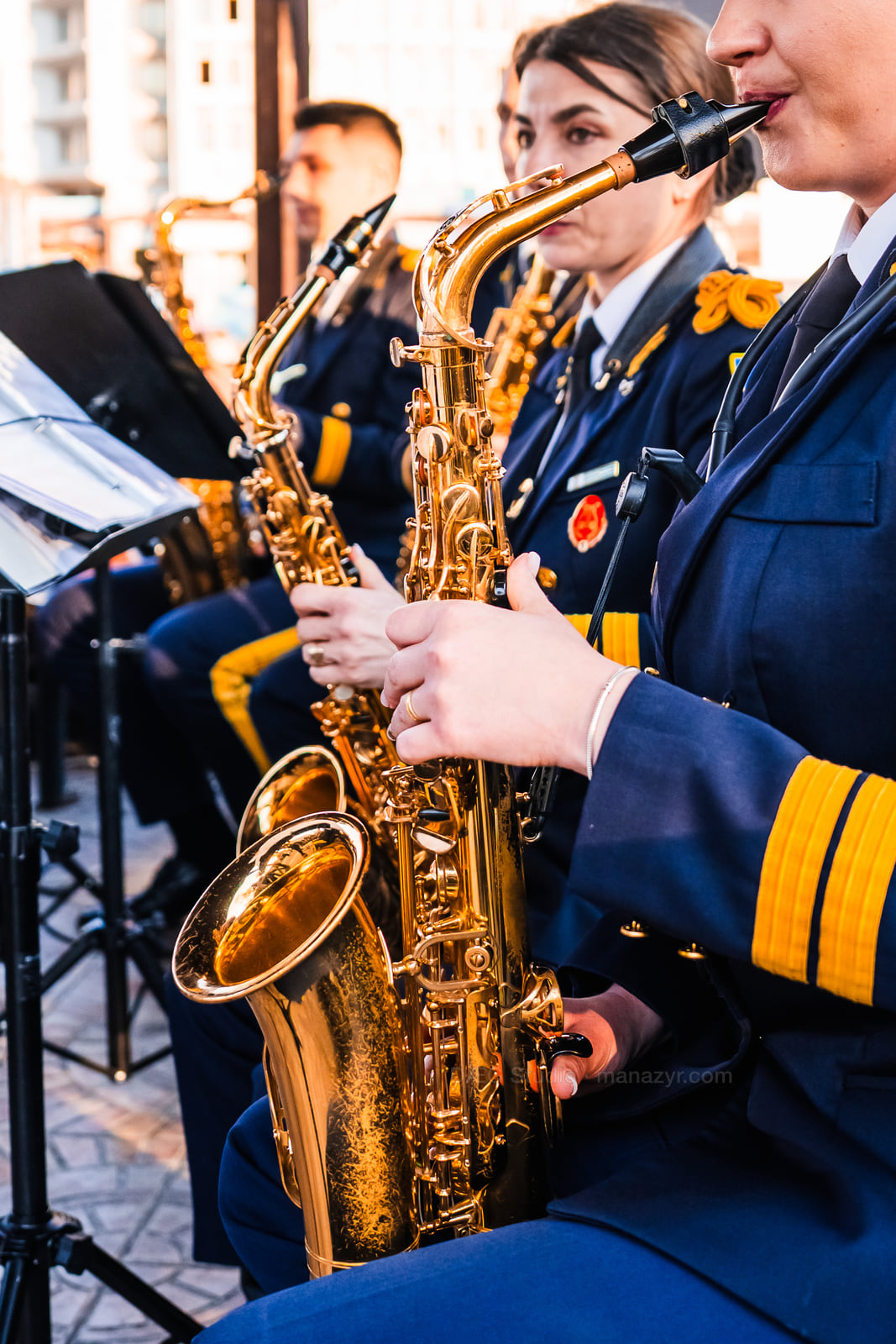 Close view of saxophones and musicians’ hands against dark blue ceremonial uniforms.