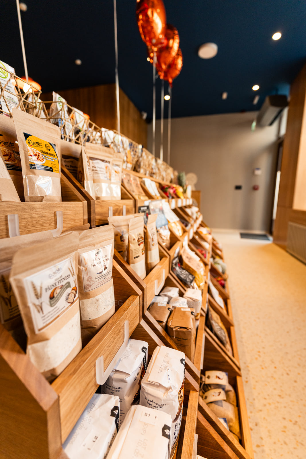 Produse alimentare ambalate, așezate în lăzi din lemn înclinate în interiorul magazinului.