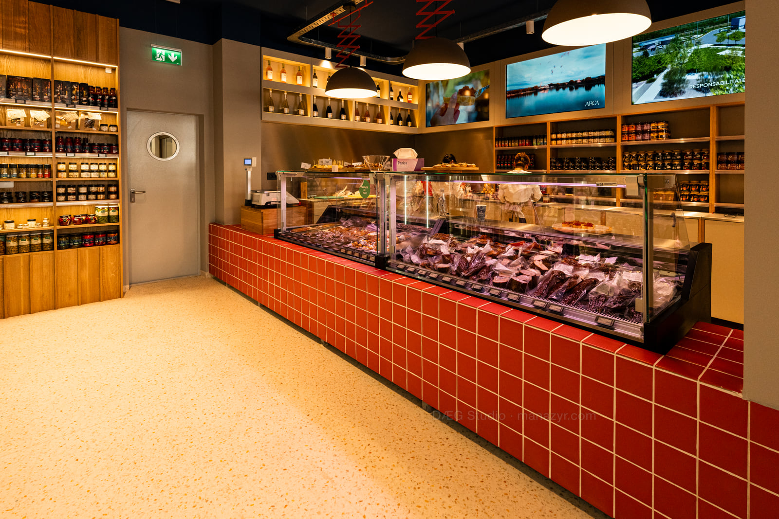Wide view of a warmly lit specialty shop with red-tiled counters and stocked shelves.