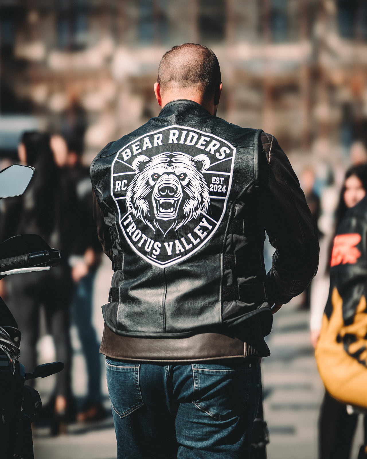 Rear view of a biker wearing a large bear-emblem leather club vest.