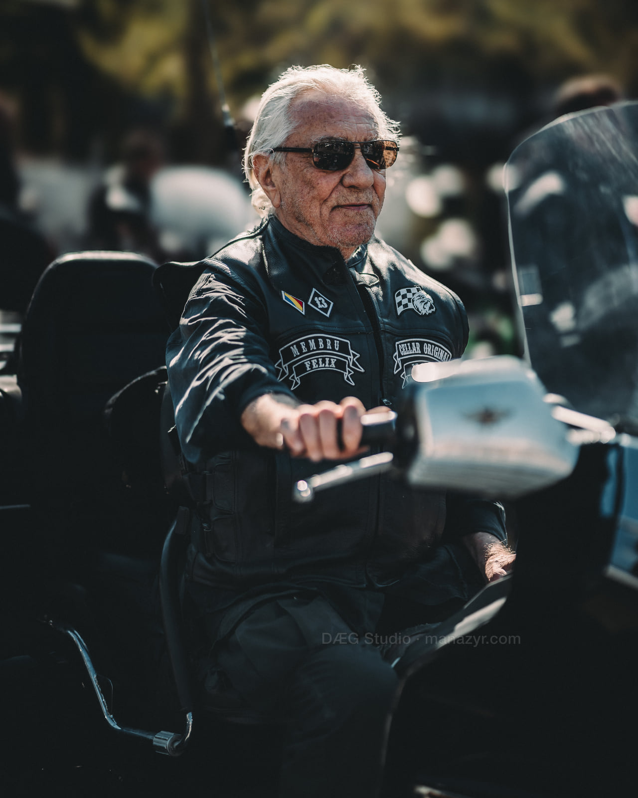 Older rider in dark sunglasses sits calmly on a touring motorcycle.